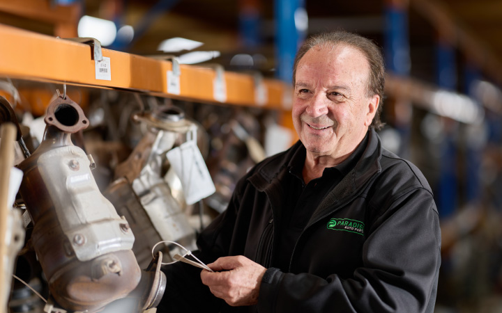 Capricorn Member at Paradise Auto Parts inspecting tagged automotive components in a well-stocked warehouse