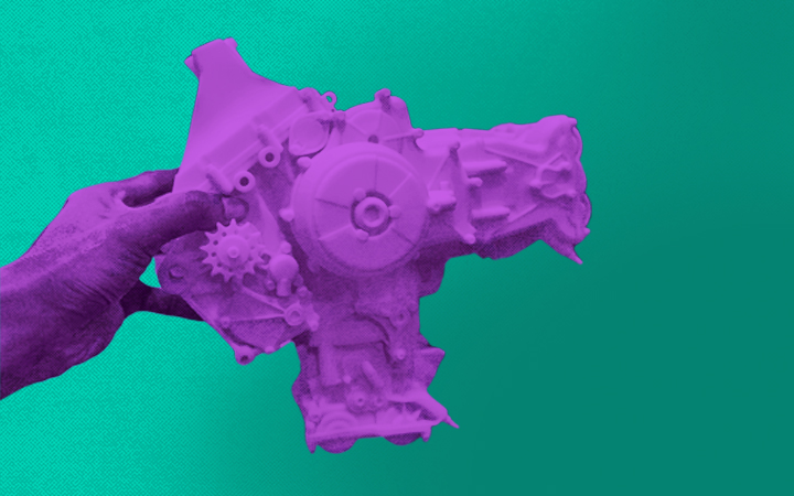 A hand holding an auto part created through 3D printing.