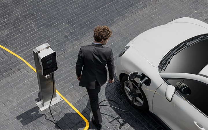 A person in a suit charging his electric car.