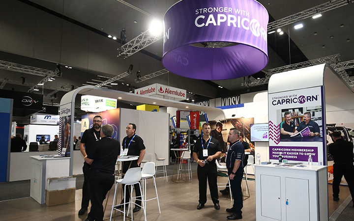 A large display at AAAExpo attracts a group of people, with Capricorn proudly standing amidst the crowd.