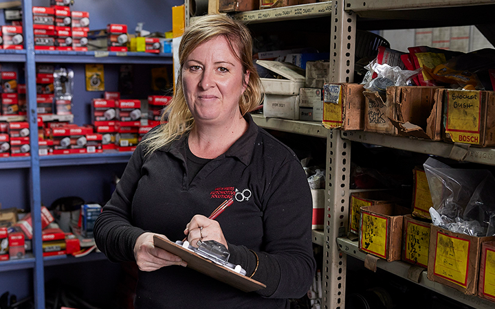 Woman taking notes and smiling to the camera in a workshop storage