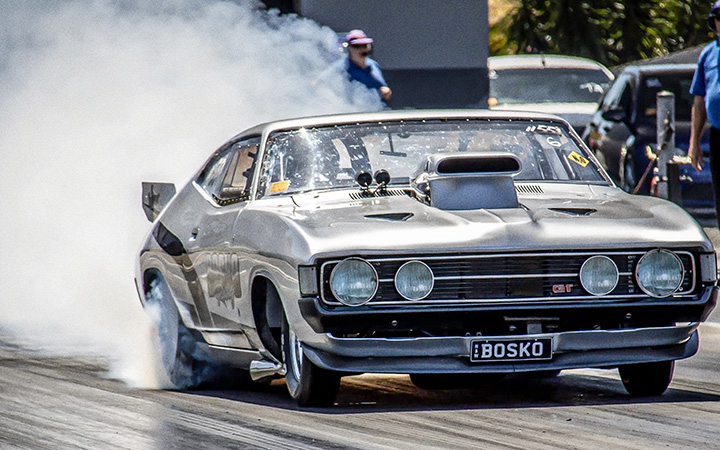 Drag car, Ford Falcon XA Coupe, billowing smoke on the track.