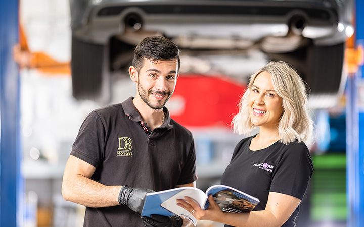 Capricorn Risk Manager showing a brochure to a Mechanic with both of them smiling to the photo