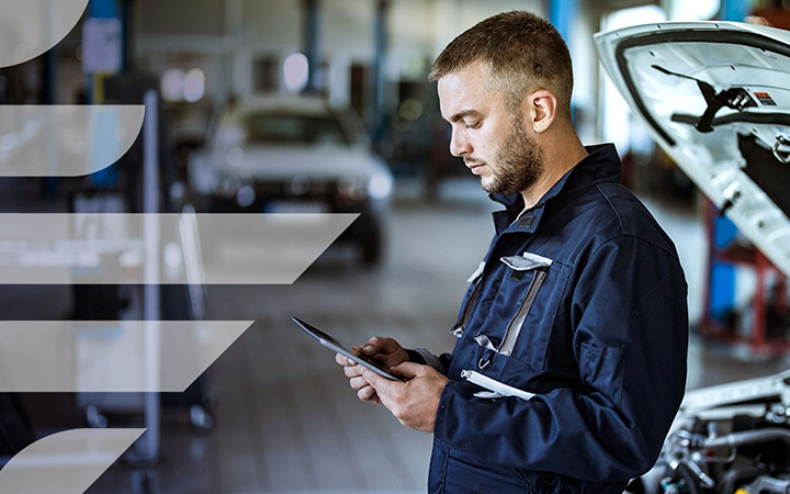 Men working on his tablet in front of a vehicle's engineer 