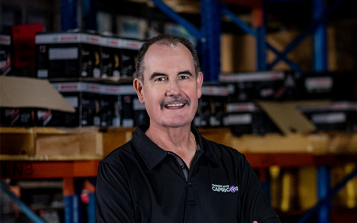 David Fraser, Capricorn Group CEO, wearing a black polo with the Capricorn logo, smiling confidently, reflecting his leadership and career legacy.