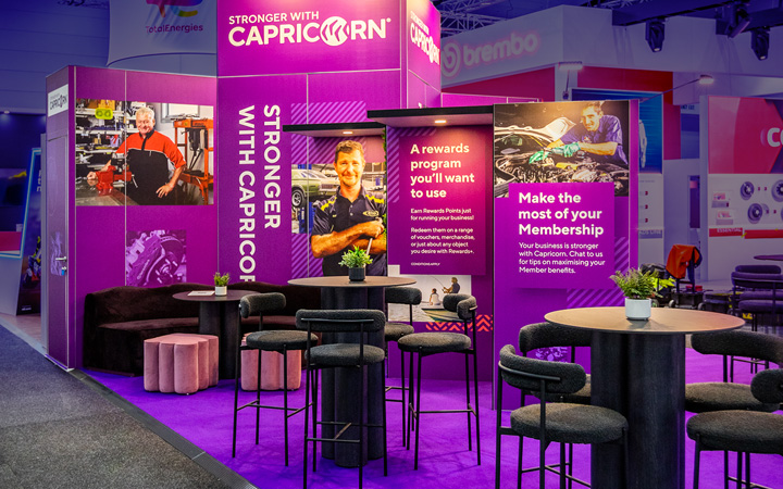 Capricorn booth with table and chairs in purple and black color scheme.