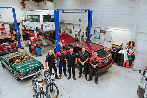 Roy Turner, a Capricorn Area Manager and the Roy Turner Automotive team standing next to the e-bikes inside the workshop.