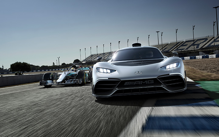 The Mercedes-AMG ONE hypercar displayed on the track alongside a Mercedes F1 car, showcasing cutting-edge automotive design.