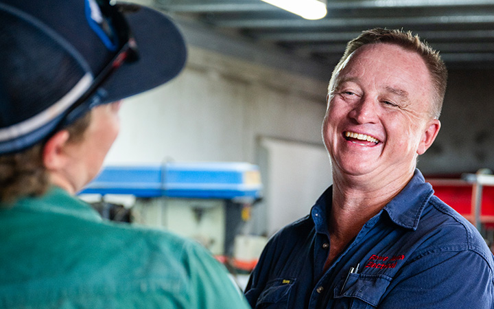 Mark Rowe smiling while talking with someone.