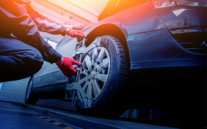 Hands using wheel balancing tool on car tyre.
