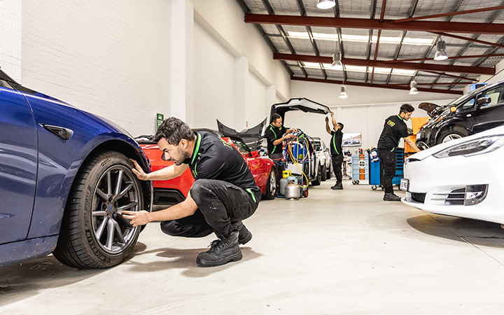 Mechanics working on different types of car in a workshop