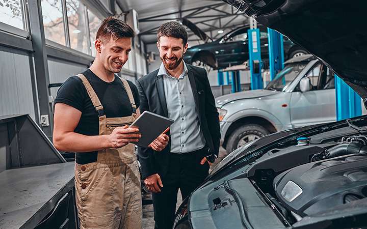 A person showing on information to another one on his table in front of a vehicle's engineer