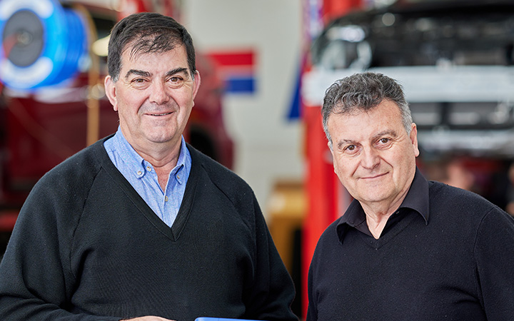 Two men, Larry and Frank Napoli, are seen in a car repair shop, holding a tablet.