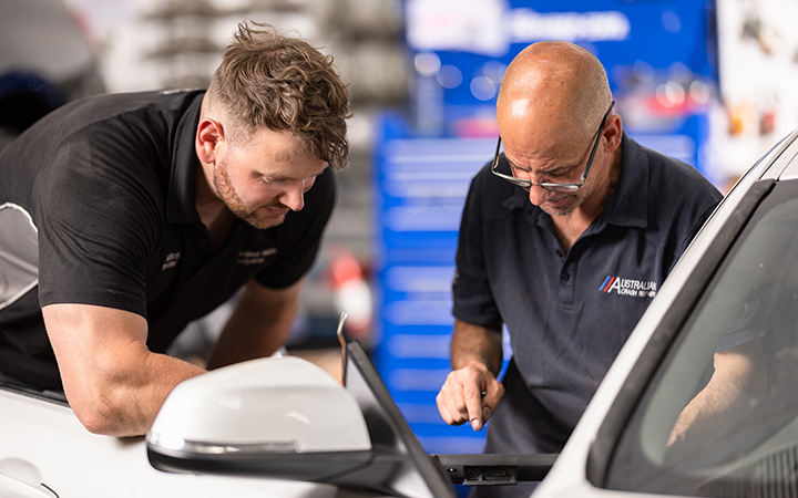 Two mechanics working on a vehicle's engineer.
