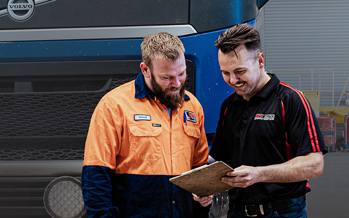 Two mechanics looking an information in a paper sheet in a workshop