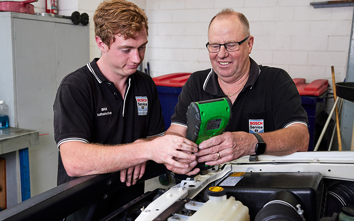 Two mechanics performing maintenance on a vehicle in a workshop.