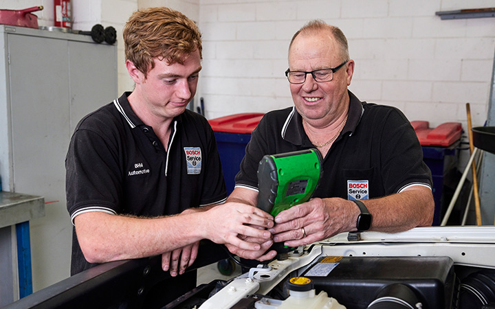 A mechanic and an apprentice working on an vehicle