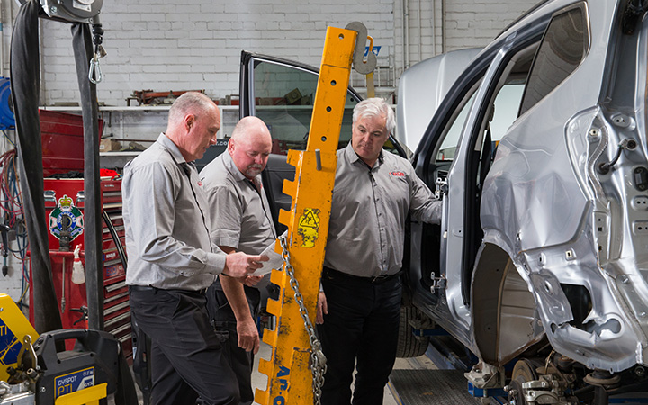 Auto technicians repairing a car in a garage.