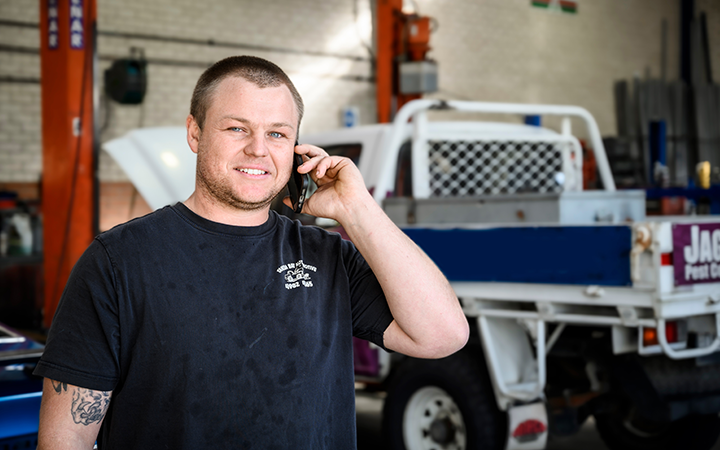 Men on a mobile phone call smiling to the camera in a garage