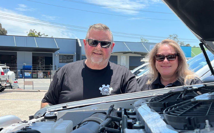 Gavin McCarthy and Jade Burgmann standing beside a car engine