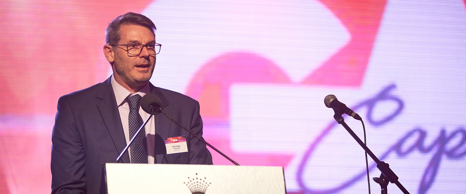 A Capricorn Member in formal attire stands at a stage, representing the Capricorn Member Director during a Gala Dinner event.