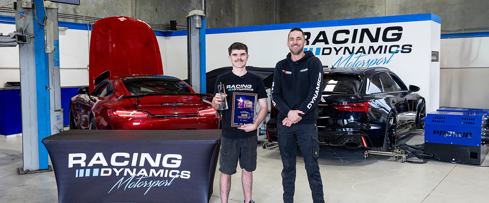 Hudson Rhodes, 2025 Capricorn Rising Stars WA Region Winner, proudly holding his award alongside a colleague at Racing Dynamics, with high-performance cars in the background.