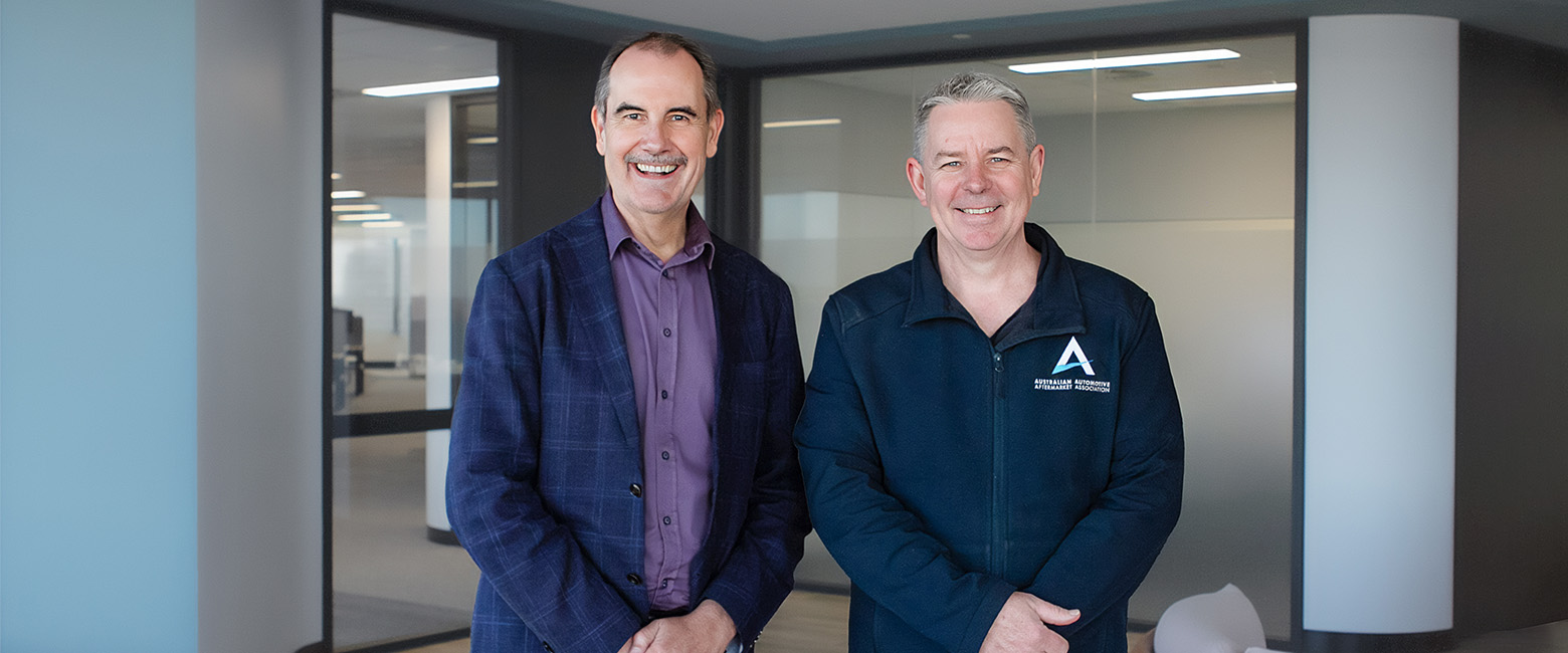 David and Stuart standing side by side smiling at the camera in an office environment