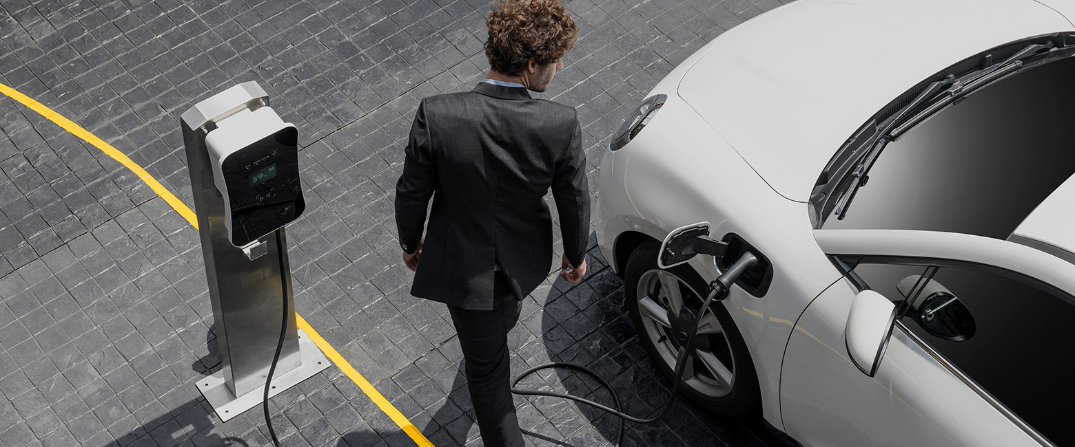 A person in a suit charging his electric car.