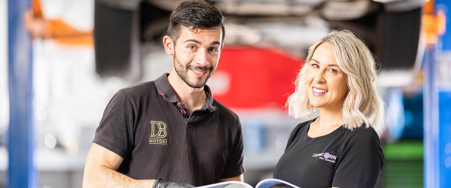 Capricorn Risk Manager showing a brochure to a Mechanic with both of them smiling to the photo