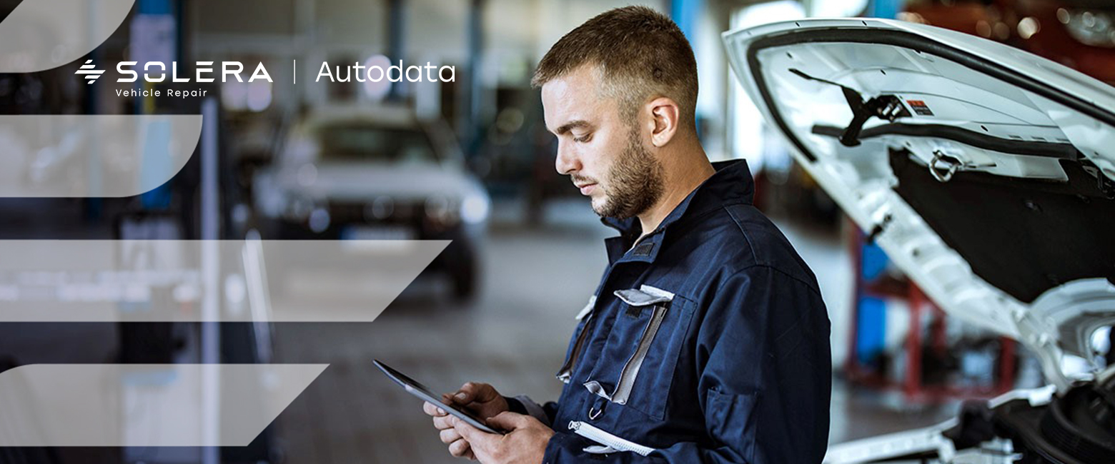 Men working on his tablet in front of a vehicle's engineer