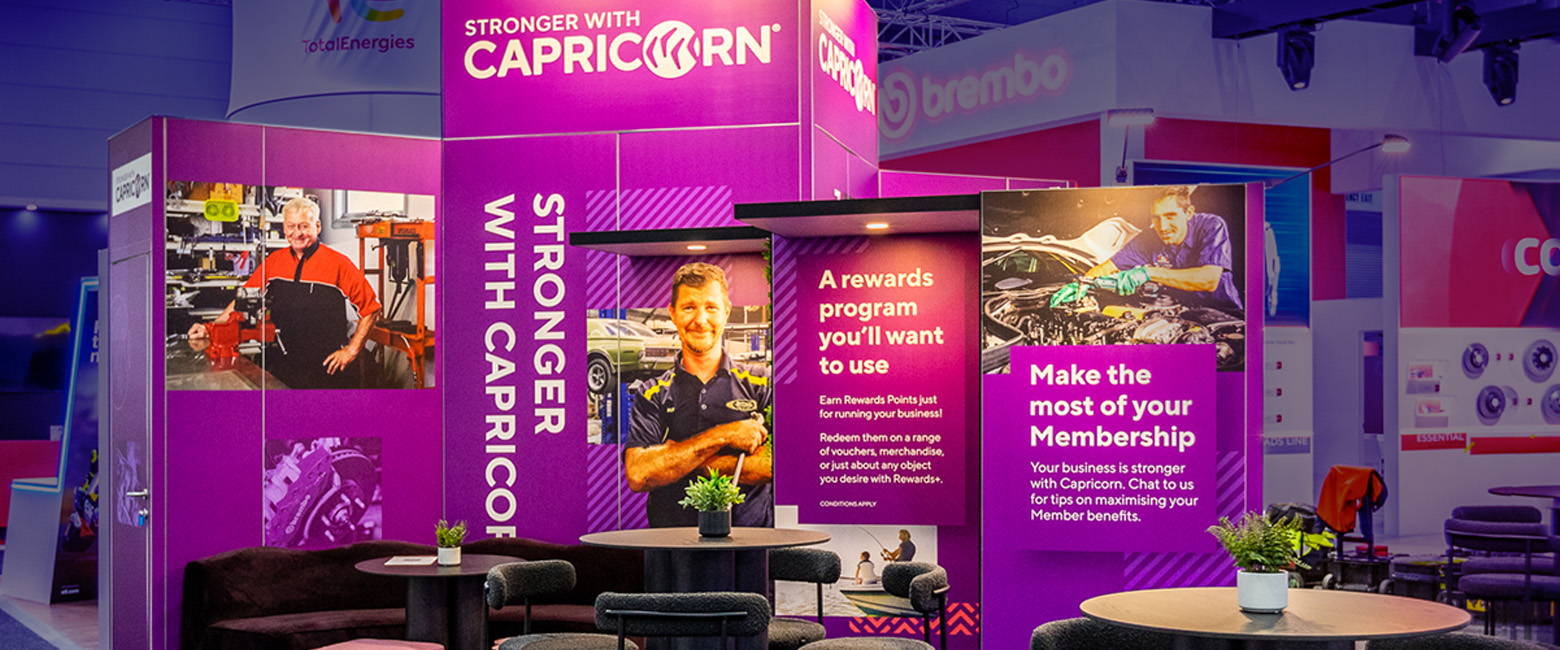 Capricorn booth with table and chairs in purple and black color scheme.