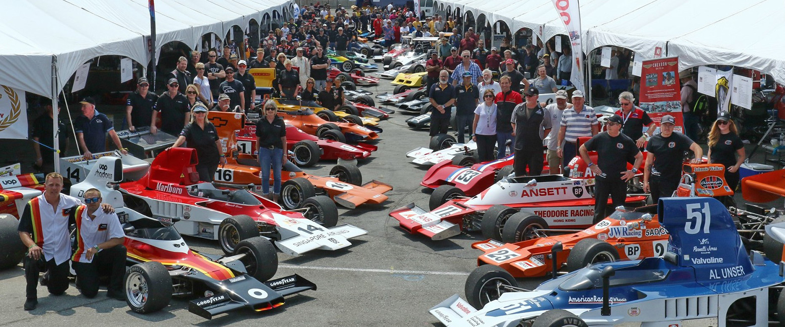 People gathered around a lineup of race cars at the 2023 Rolex Monterey Motorsports Reunion