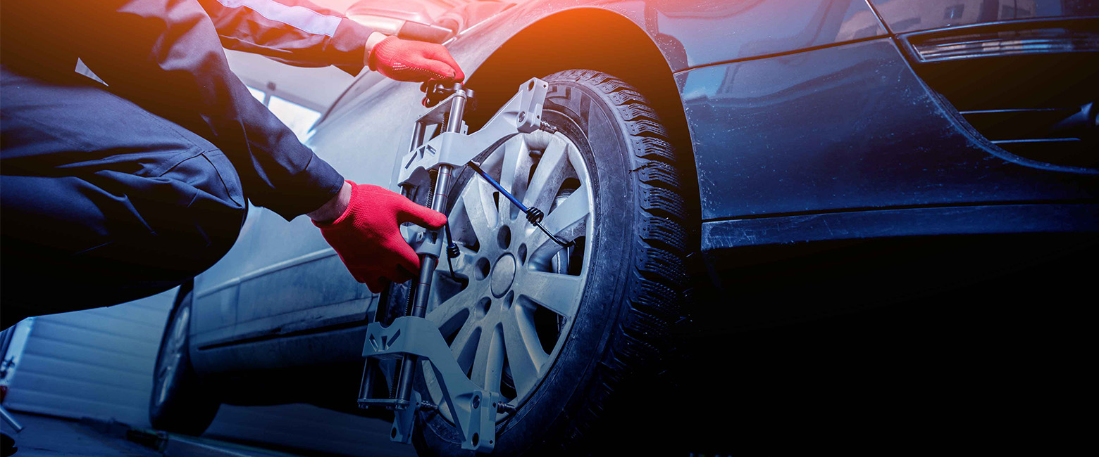Hands using wheel balancing tool on car tyre.