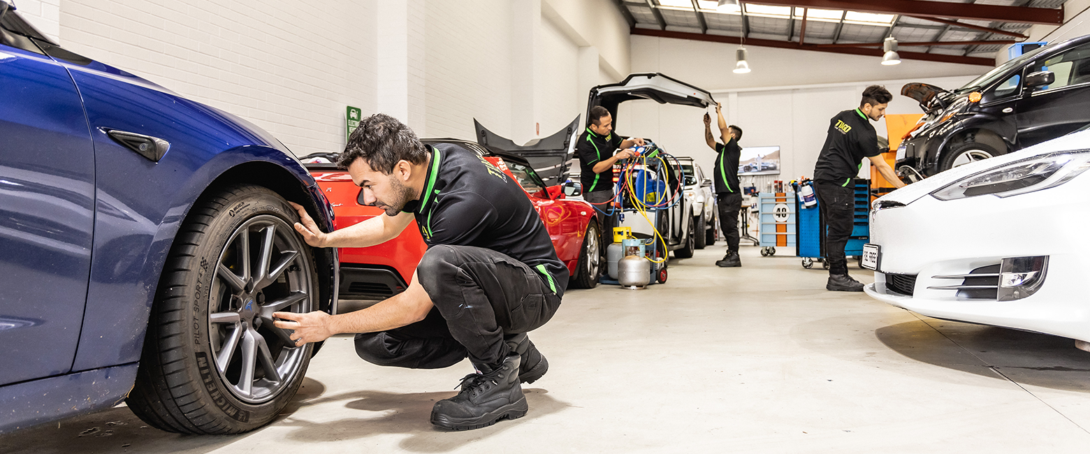 Mechanics working on different types of car in a workshop 