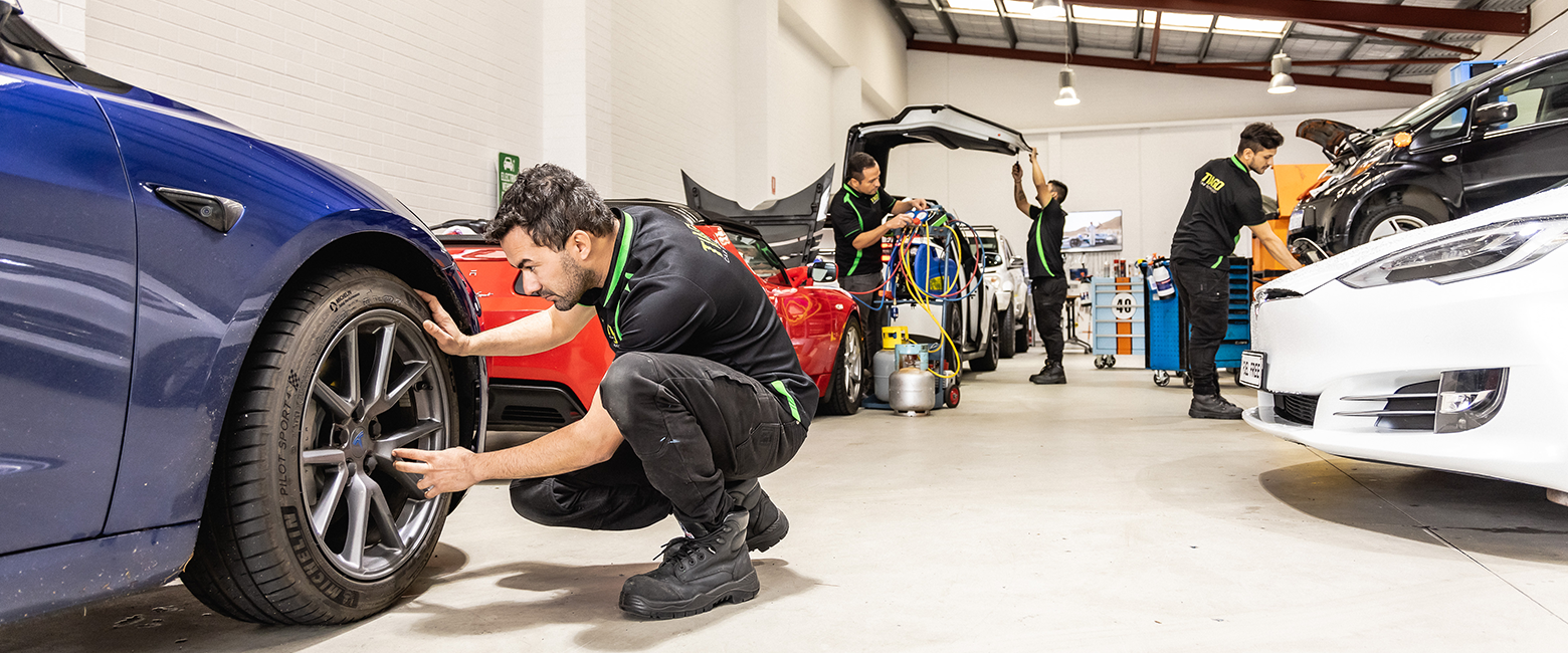 Mechanics working on different types of car in a workshop