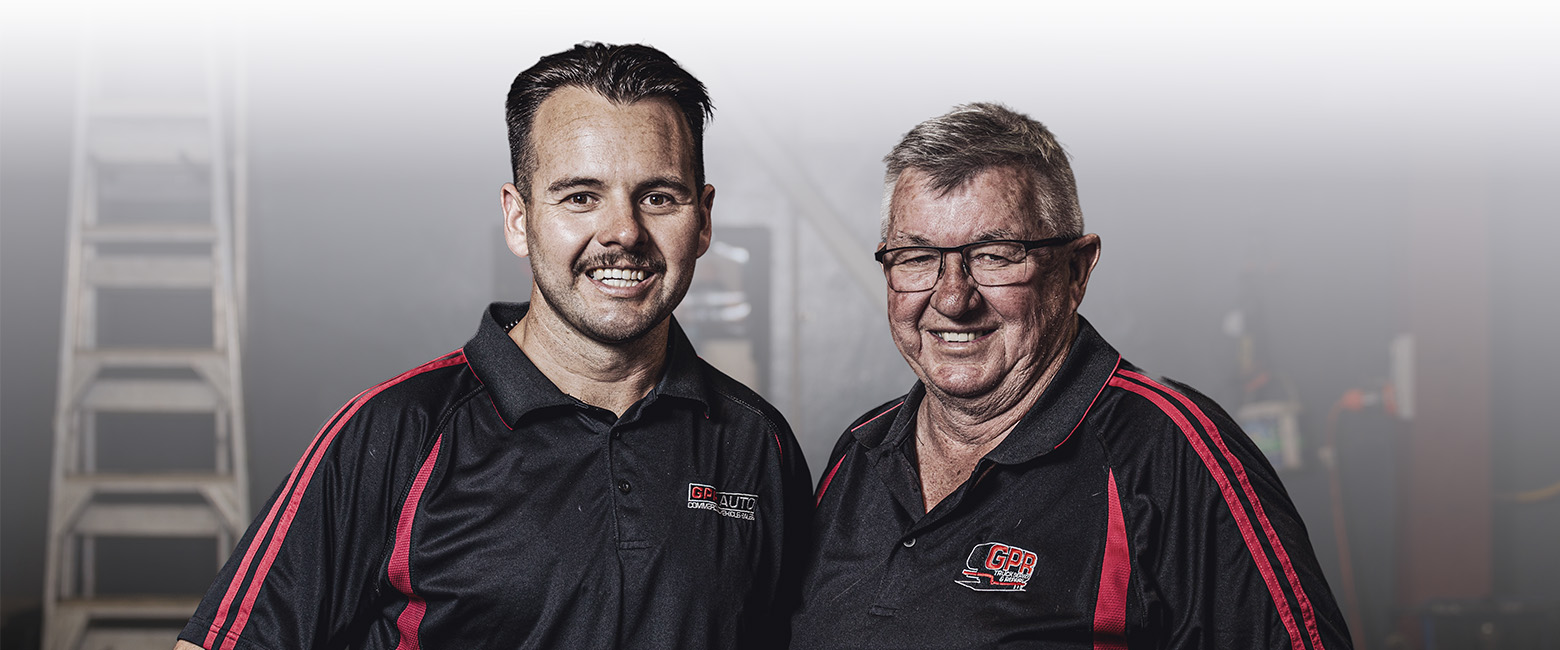 Two men in black and red shirts standing next to each other, smiling and posing for the camera.