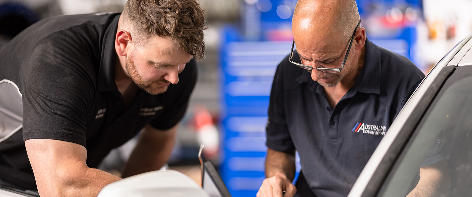 Two mechanics working on a vehicle's engineer.