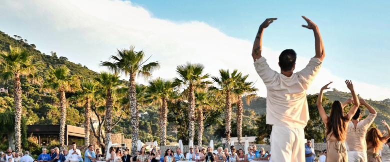Participants performing yoga poses on the beach, with a scenic ocean view during a conference event.
