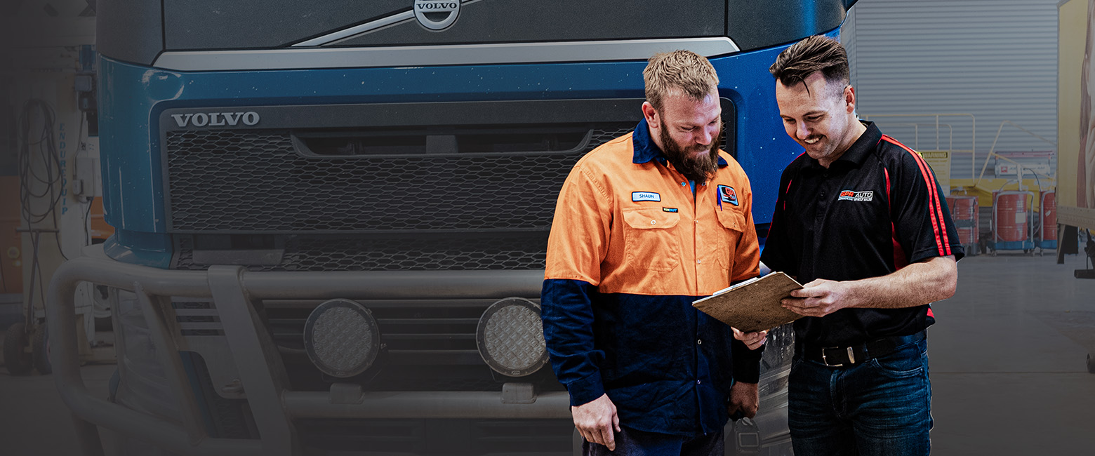 Two mechanics looking an information in a paper sheet in a workshop