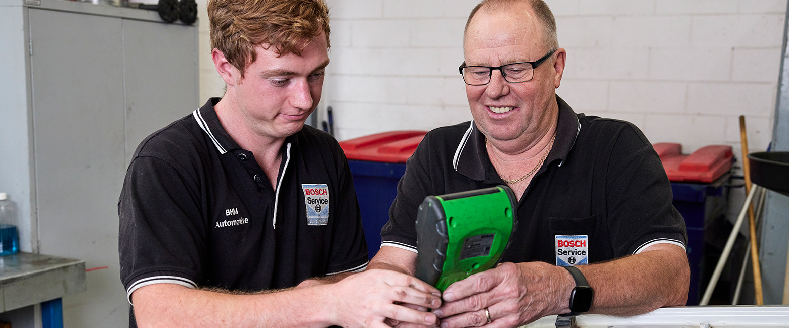 Two mechanics performing maintenance on a vehicle in a workshop.