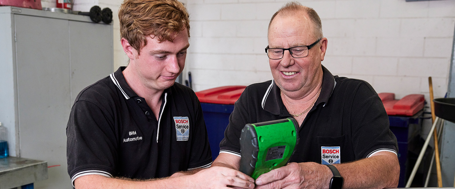 A mechanic and an apprentice working on an vehicle