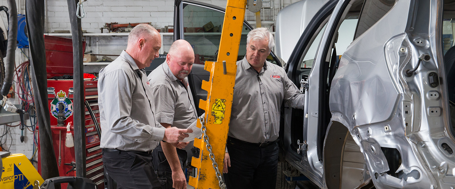 Auto technicians repairing a car in a garage.