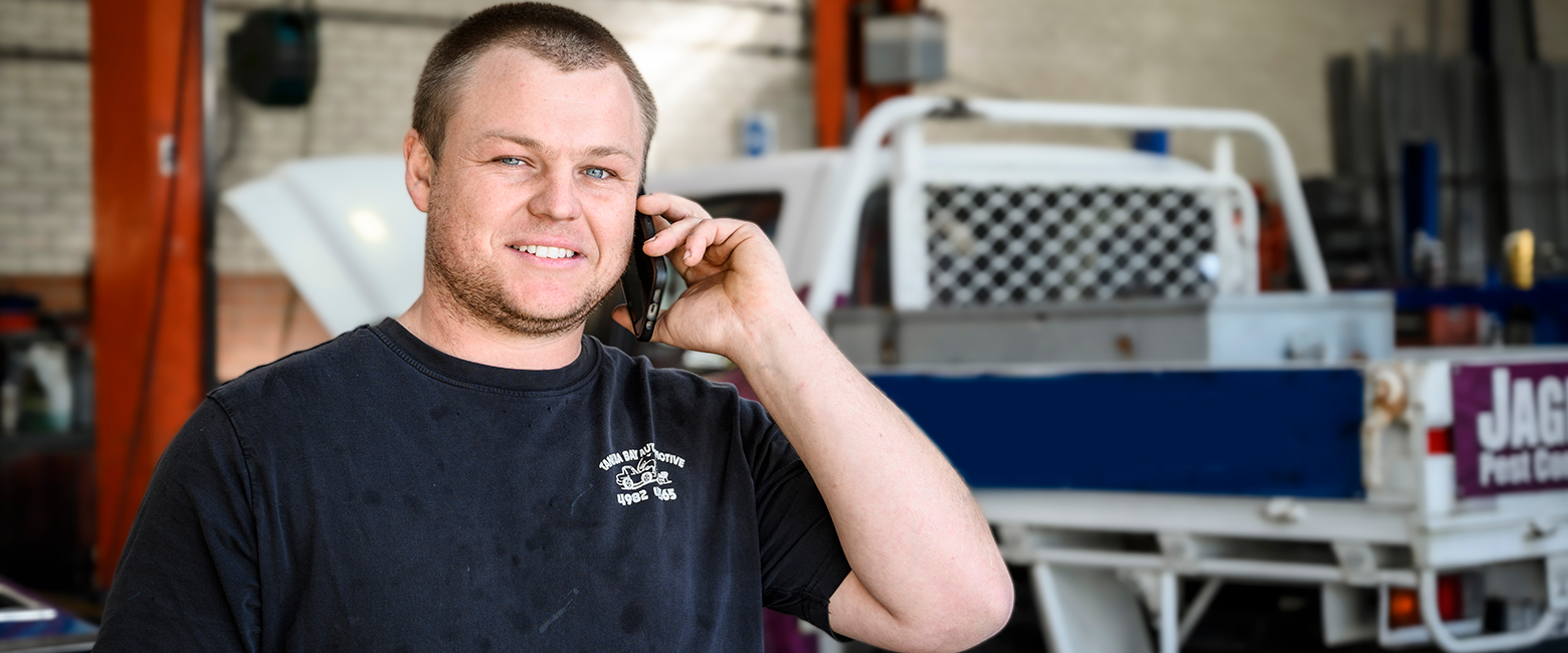 Men on a mobile phone call smiling to the camera in a garage