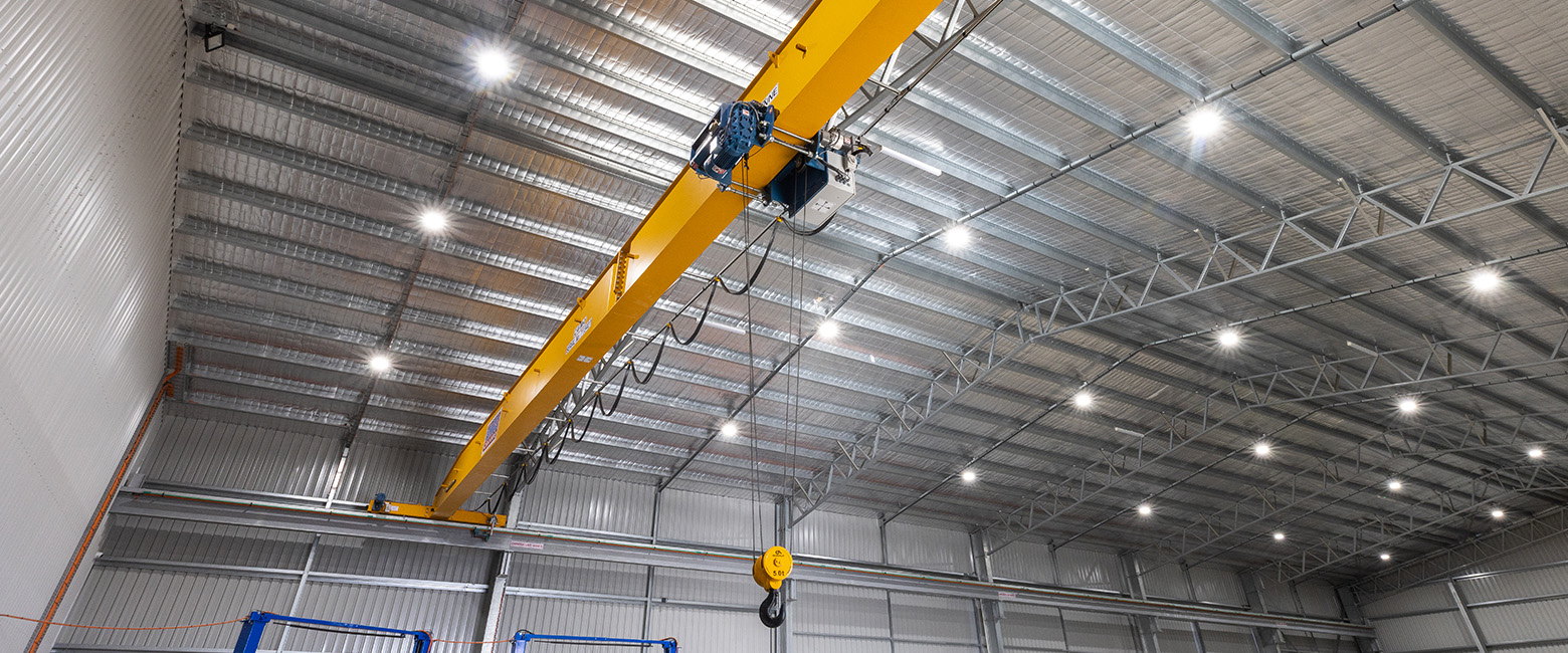 An expansive warehouse showcasing a crane, brightly lit by LED lights