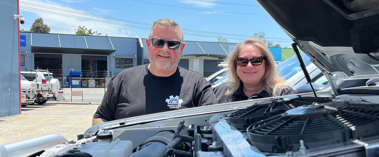 Gavin McCarthy and Jade Burgmann standing beside a car engine