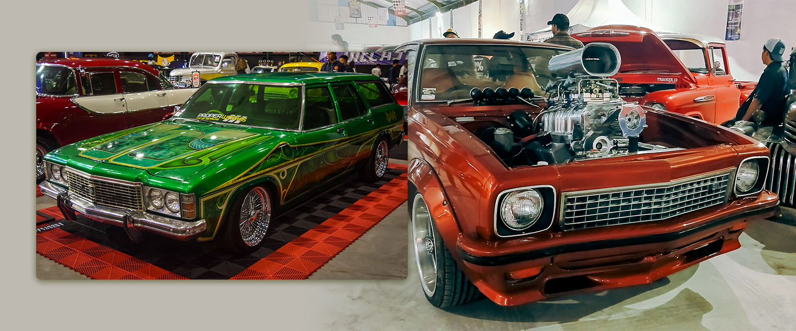 Image of two classic Holden cars: a green one on the left and a red one on the right with its engines in display.