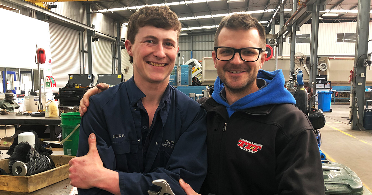 Luke North and Reilly Sanders smiling to the camera in the workshop