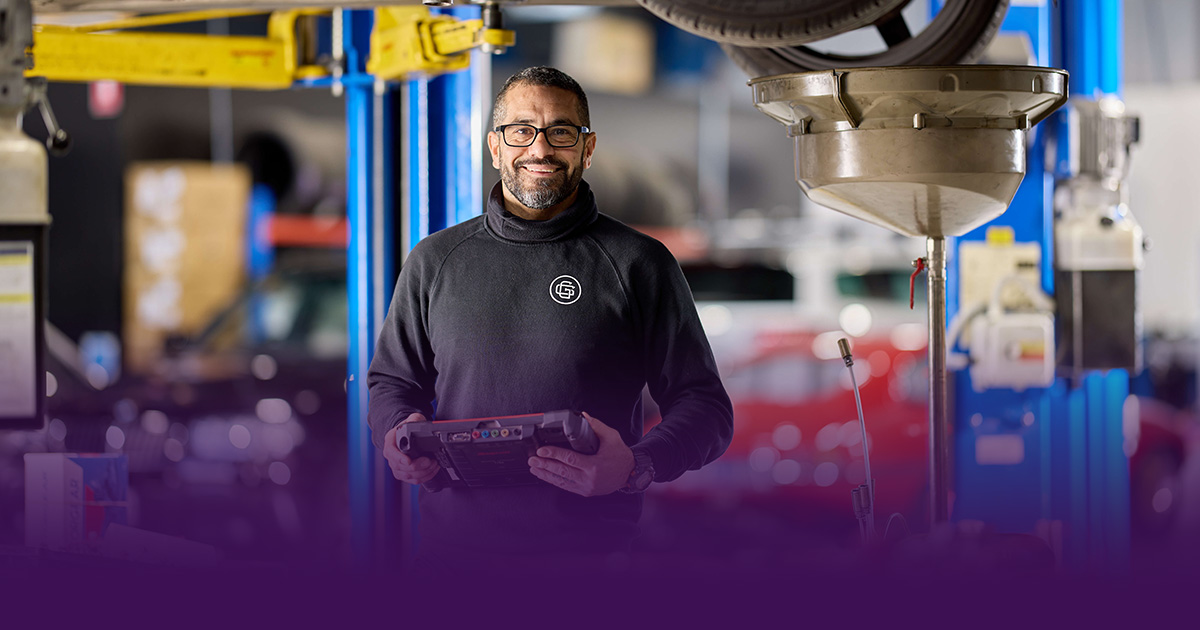 A Capricorn Member in a black shirt is smiling to the camera while standing in his workshop.