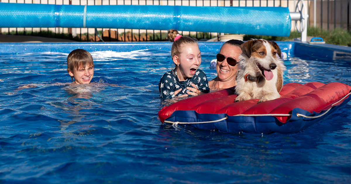 A Capricorn Member's family and their dog on a raft enjoy a sunny day in their new pool, made possible by Capricorn Rewards+.