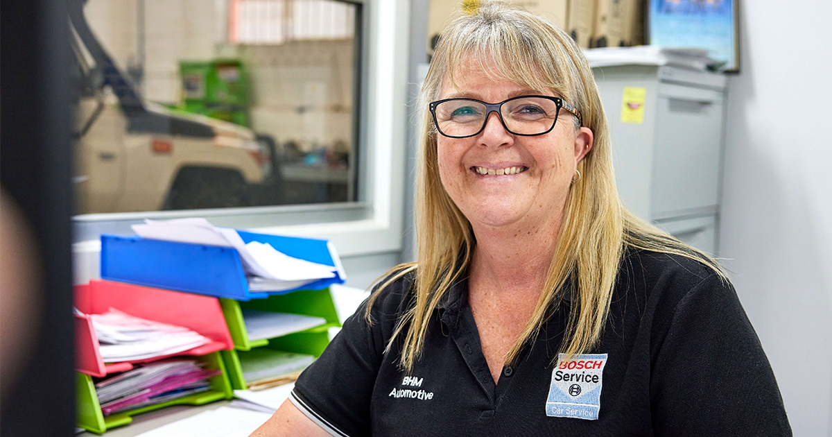 A Capricorn Member with glasses is seated at her office desk, engaged in her tasks.